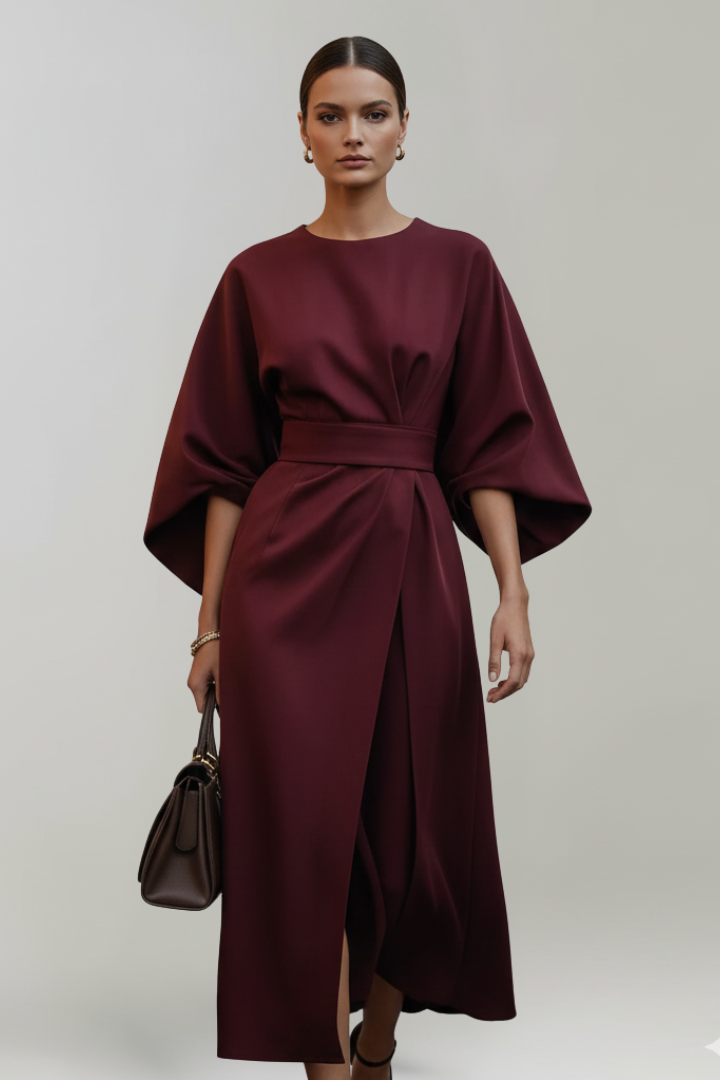 Female model showing sleeve detail of midi dress, gray background.