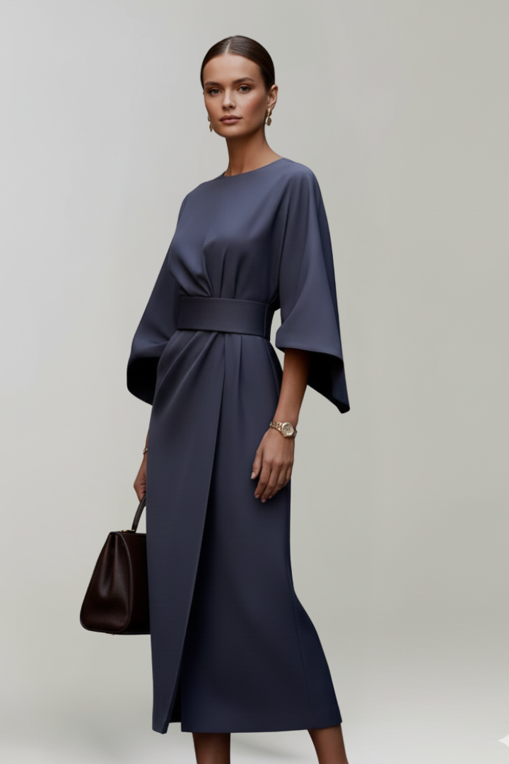 Female model posing front view in modest midi dress, gray background.