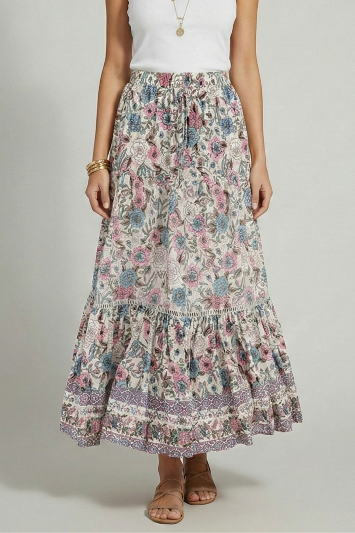 Model standing in flowy floral skirt and sandal with gray background
