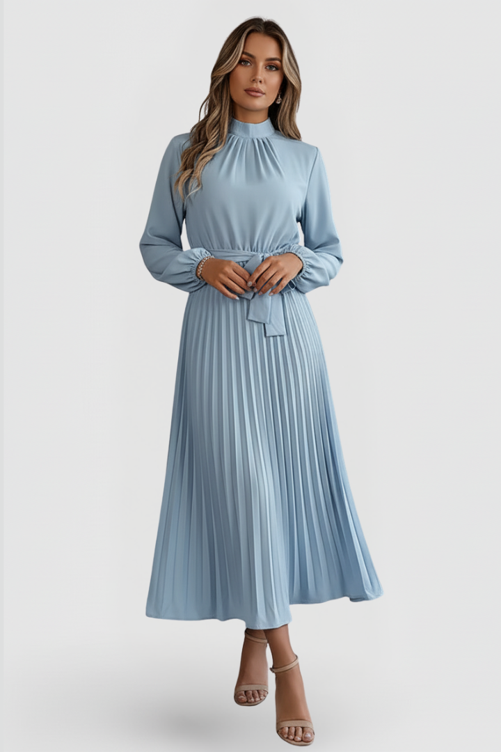 Woman wearing pleated long sleeve dress on plain gray background.