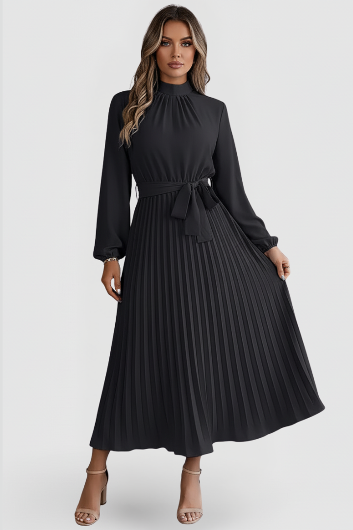 Woman wearing modest long sleeve black dress on plain gray background.