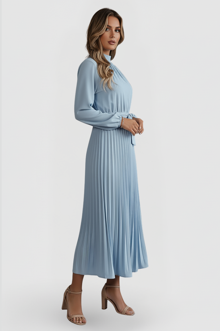 Female model posing front view in elegant pleated dress, gray background.