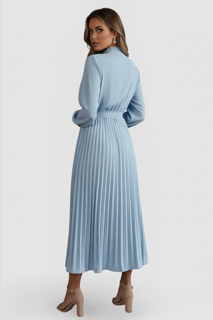Woman showing back angle of pleated dress on gray background.
