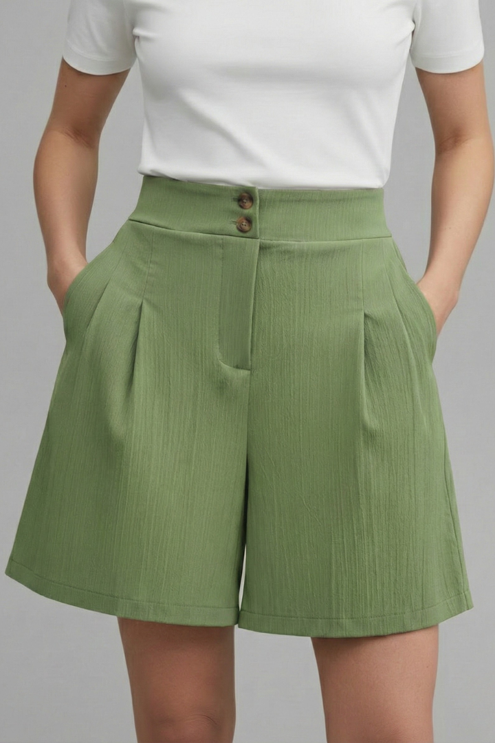 Female model showcasing tailored green shorts with pockets in plain background