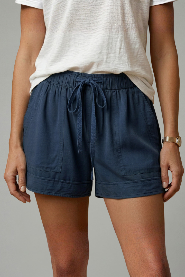 Female model in everyday blue shorts gray background