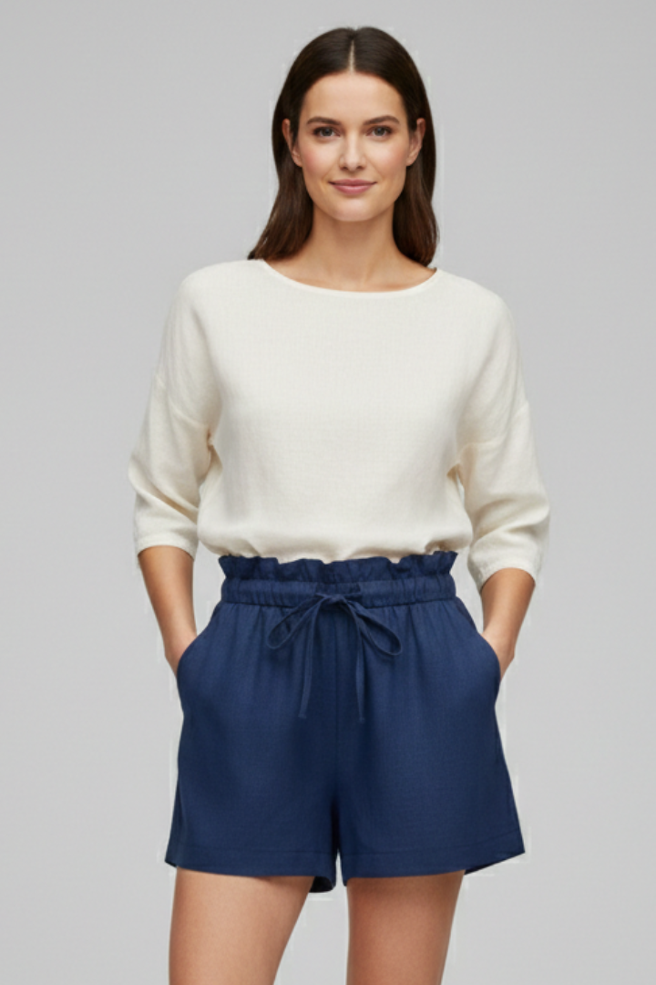 Female model wearing textured shorts and white top on gray background