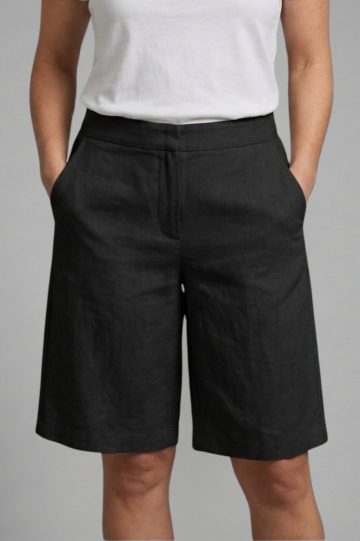 Model standing in casual black shorts, gray background