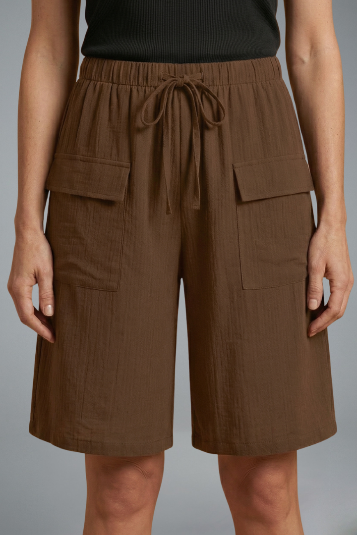 Woman in brown shorts, front angle, plain gray background
