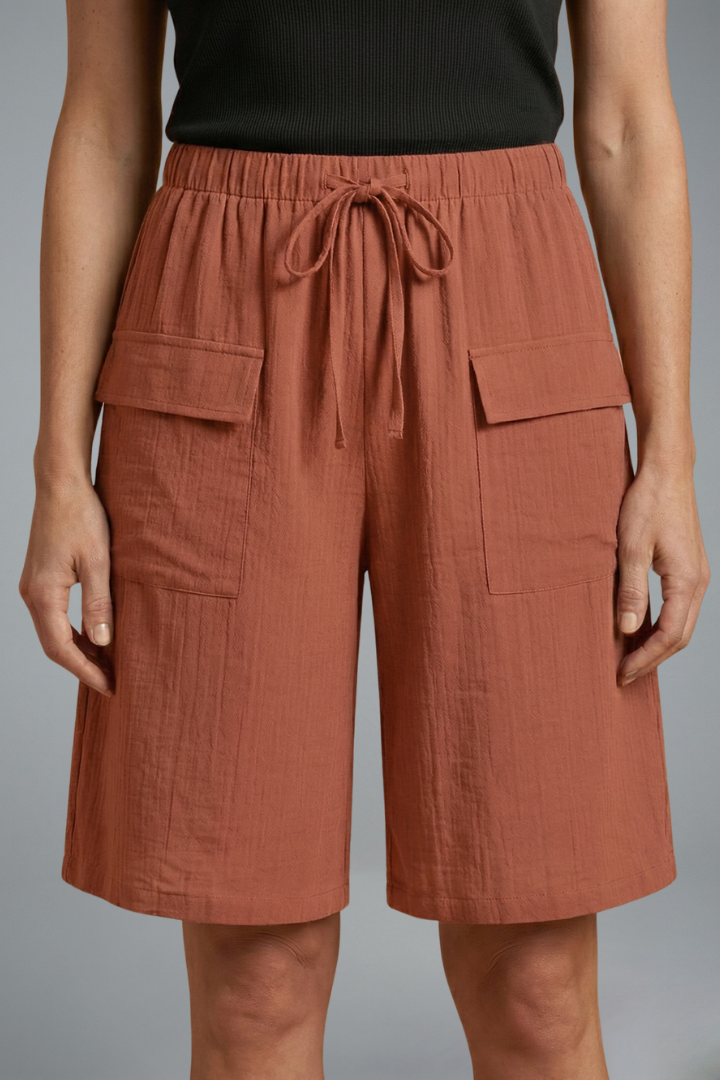 Woman wearing adjustable waist shorts, front view, plain gray background