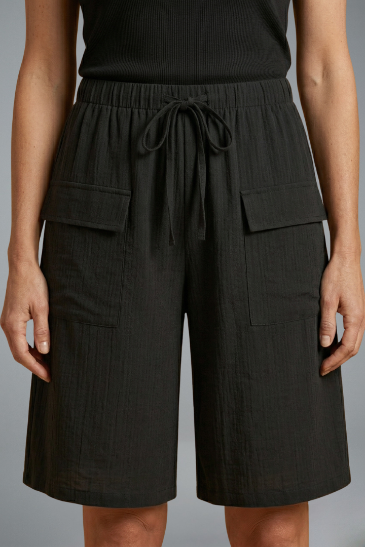 Drawstring black shorts posing straight, plain gray studio background