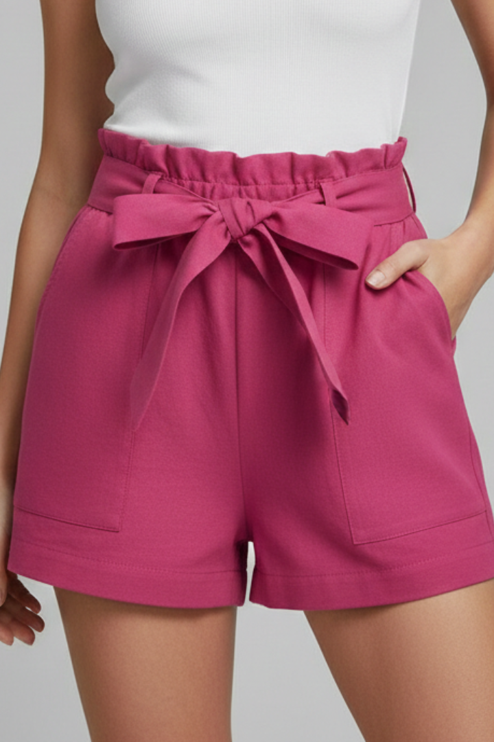 Female model minimal pose with textured shorts pink in plain background