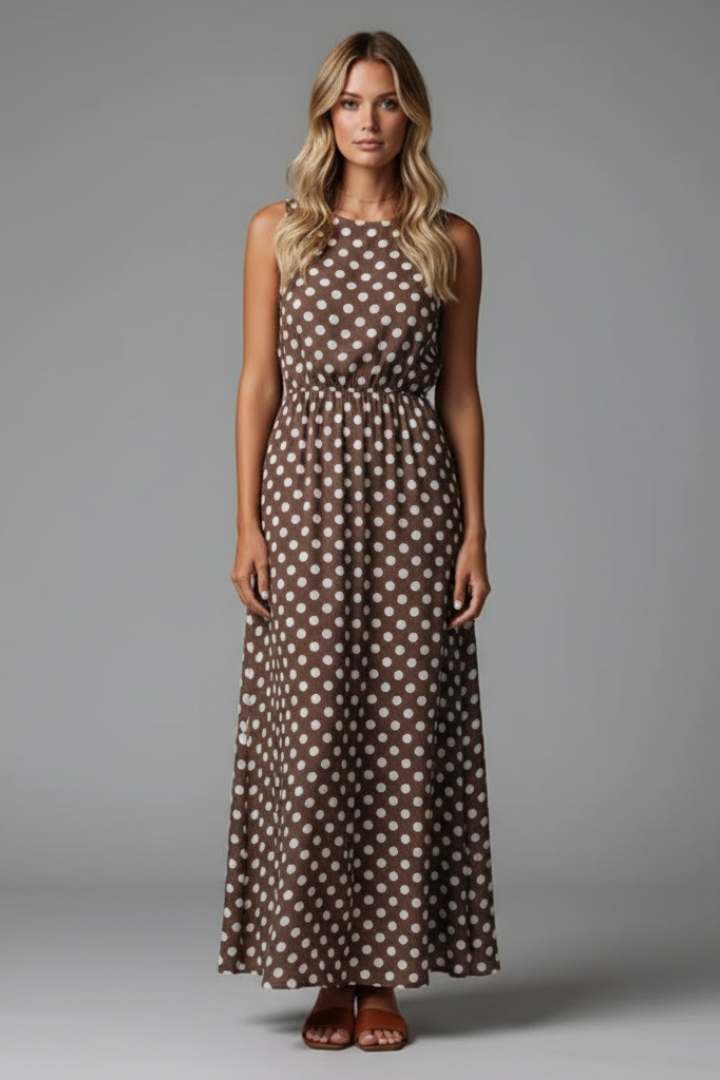 Female model walking showcasing flowy maxi dress front gray background
