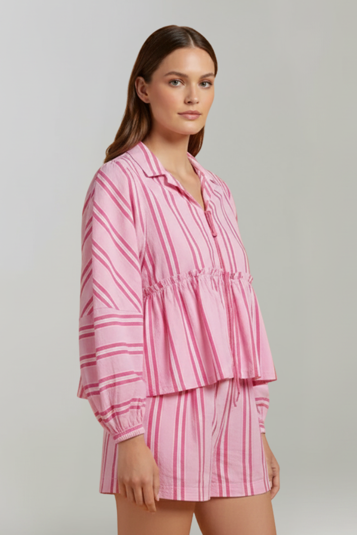 Woman wearing striped long sleeve set standing sideways on plain gray background