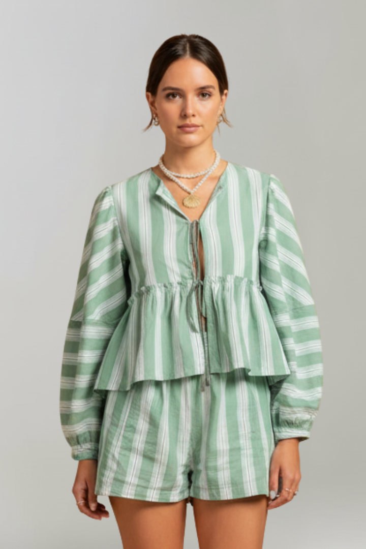 Woman standing relaxed wearing striped green set on plain gray background style