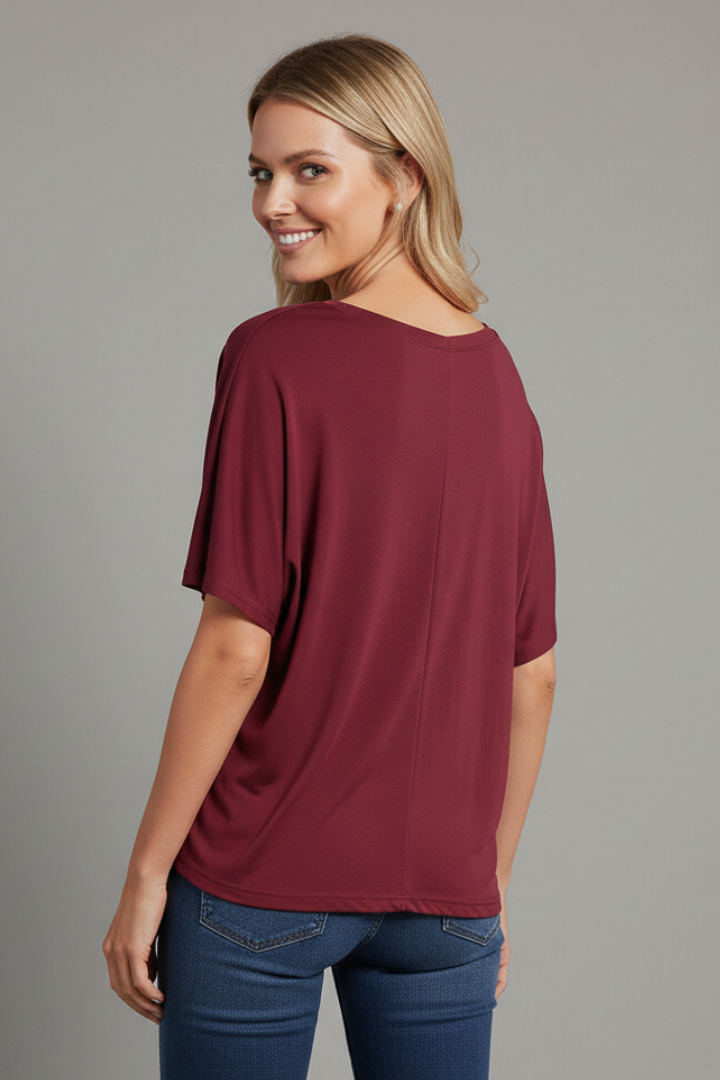 Back view model in loose short sleeve burgundy top with jeans