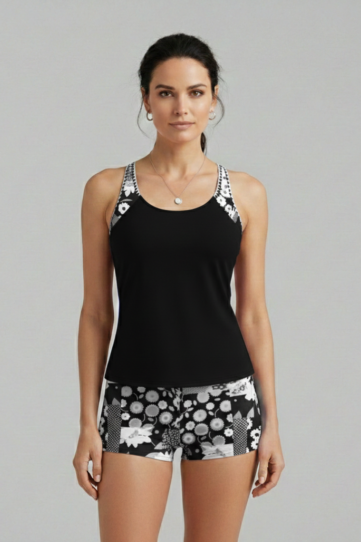 Woman wearing sleeveless black tankini set in gray backdrop view