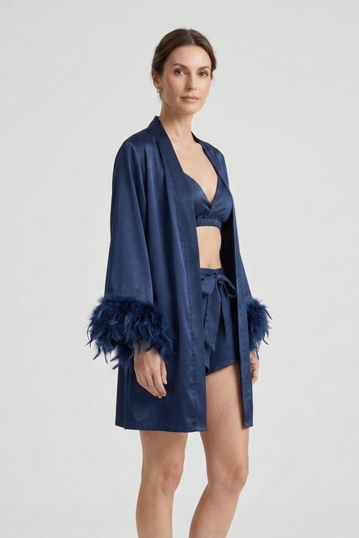 Side model posing in feather cuff robe on gray background.