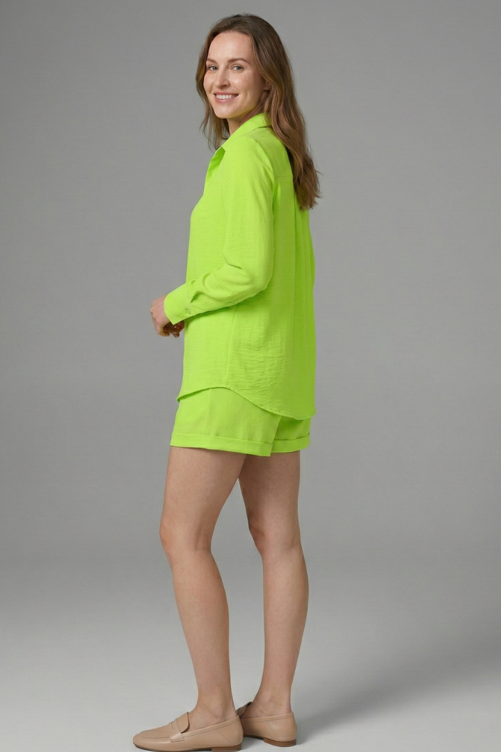 Woman showing straight hem green shirt on plain gray background studio