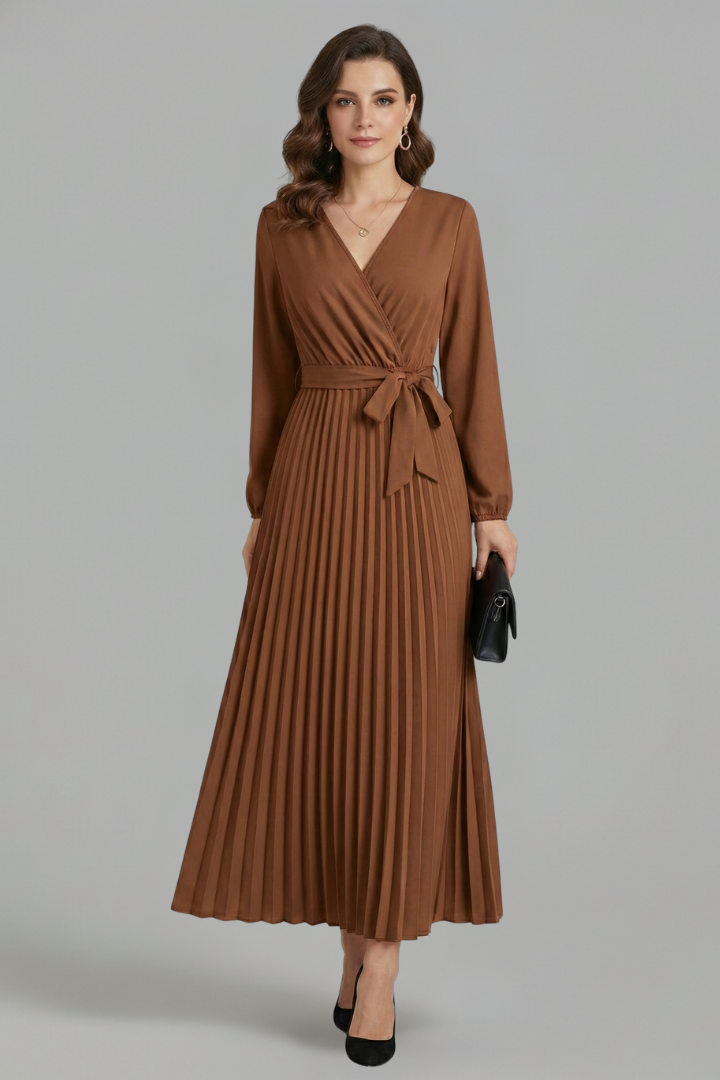 Model with clutch  and pointed heels front angle wearing a tie waist dress with gray backdrop