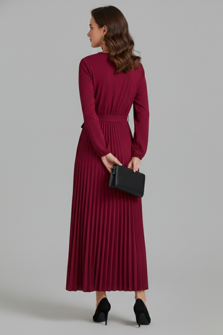 Female model holding a clutch back view pleated maxi dress gray background