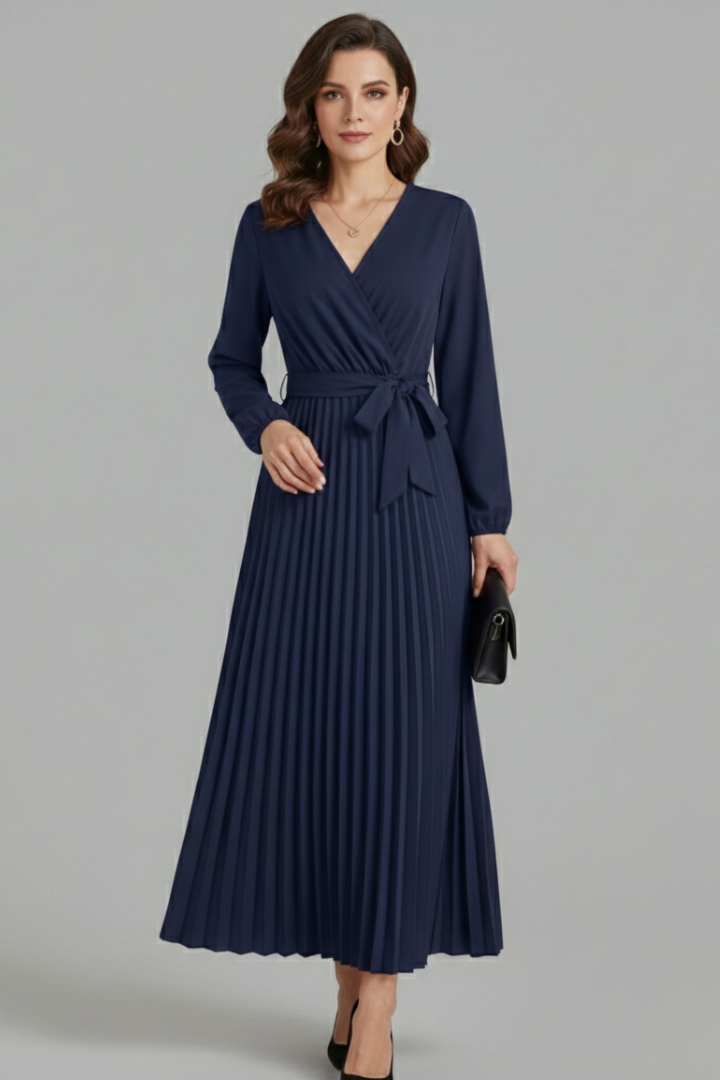 Female model standing still wearing pleated maxi dress with clutch and heels
