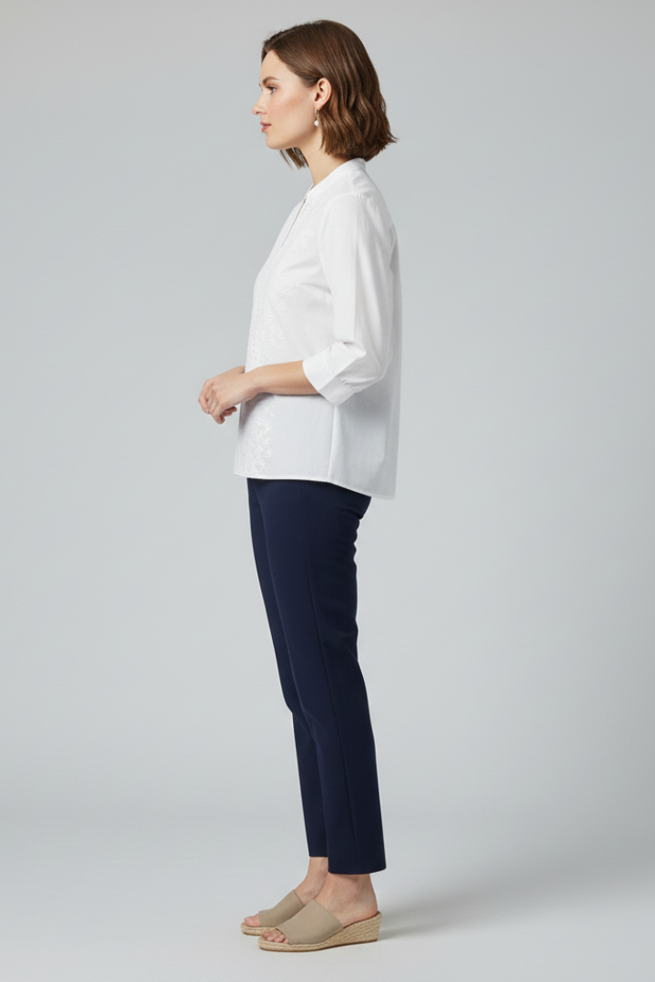 Side facing model in white blouse and trousers