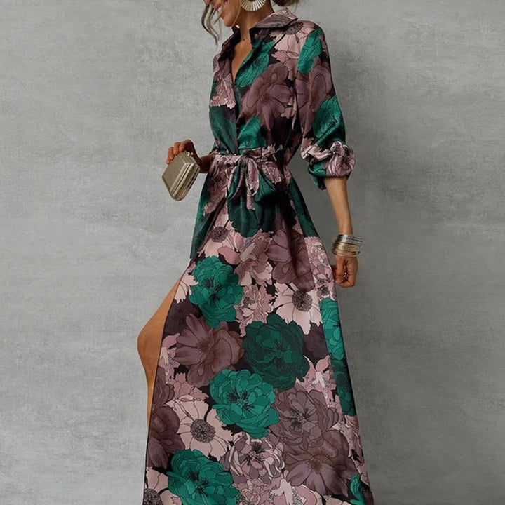 Woman posing in a long sleeve floral maxi dress with waist tie on a plain background.