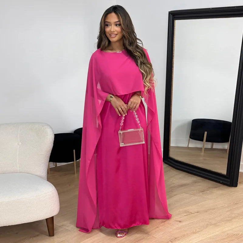 Woman in a minimalist evening maxi dress with graceful movement on a plain background.