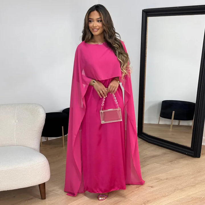 Woman in a minimalist evening maxi dress with graceful movement on a plain background.