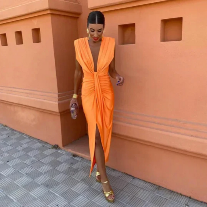 Female model in a sleeveless evening maxi dress with front slit detail on a plain background.