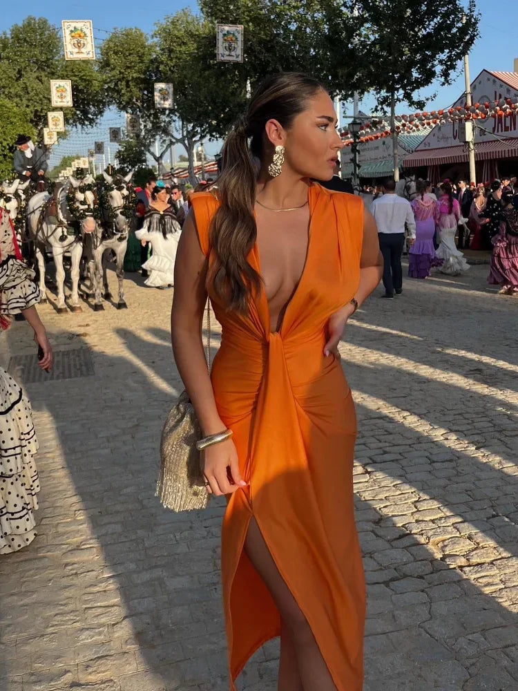 Woman posing in a flowing sleeveless maxi dress with gathered detailing on a crowded background.