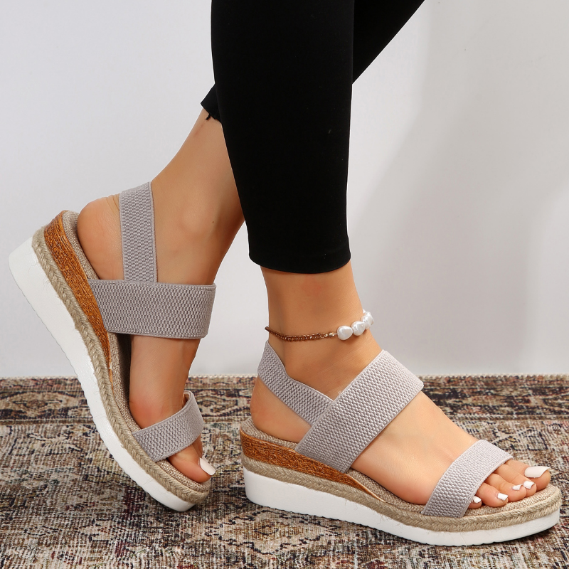 Foot model in open-toe sandals with rustic floor background.