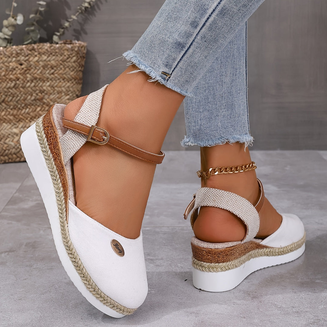 Close-up foot wearing wedge sandals on smooth gray floor