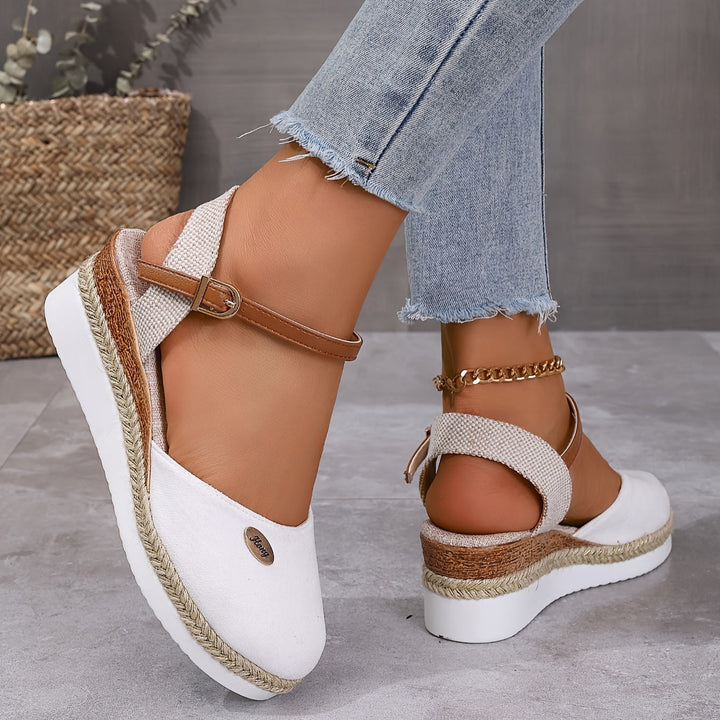 Close-up foot wearing wedge sandals on smooth gray floor