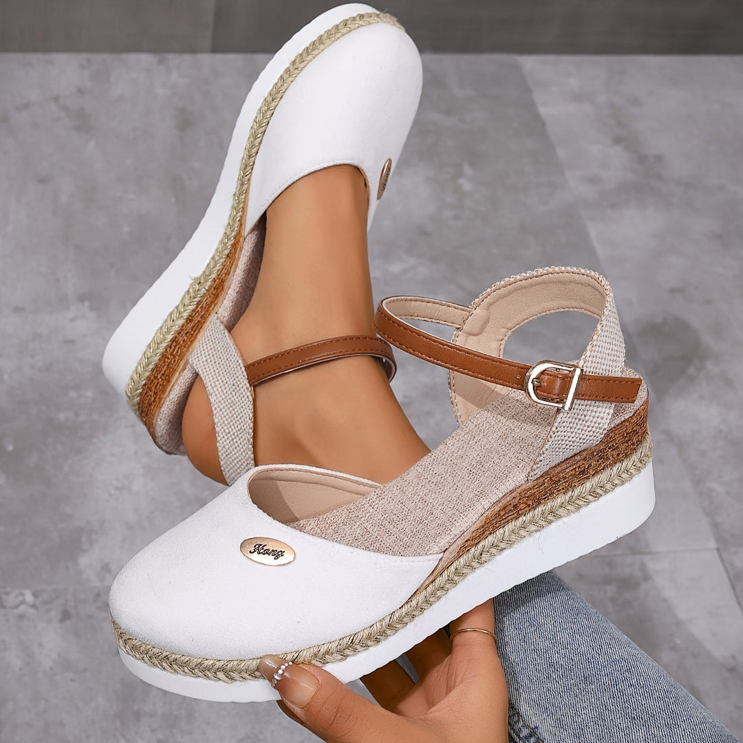 Angled side view foot in sandals against gray floor background