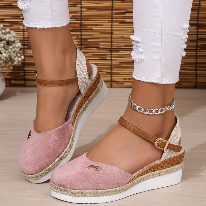 Slight angle foot wearing chic sandals on gray floor surface