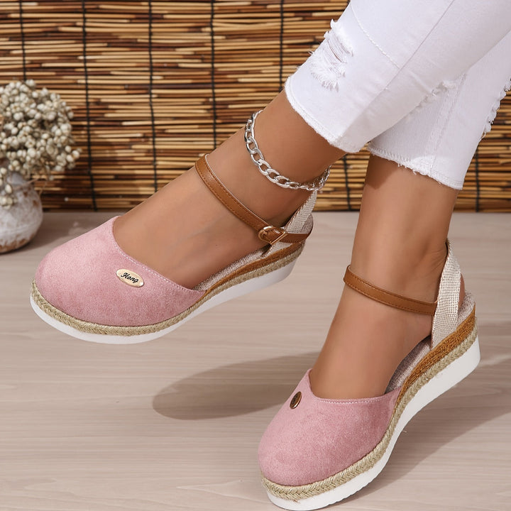 Close-up side foot wearing sandals on neutral gray floor