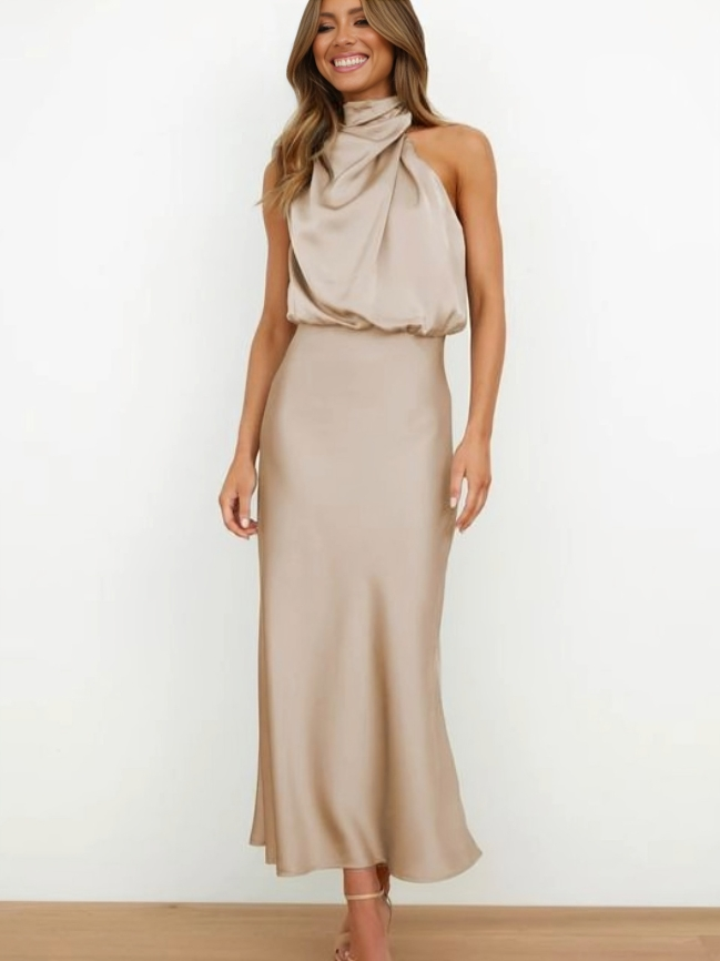Woman showcasing a sleek halter formal dress on a plain backdrop.