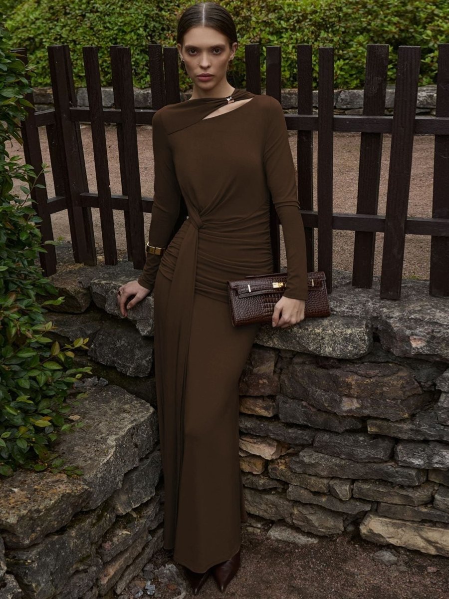  Woman showcasing a fitted maxi evening dress with graceful gathered detail on a plain background.