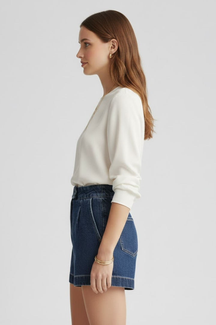 Female model side angle wearing high-rise denim shorts gray background