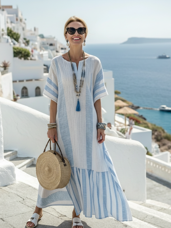 Woman wearing a striped short sleeve maxi dress on a beach background.