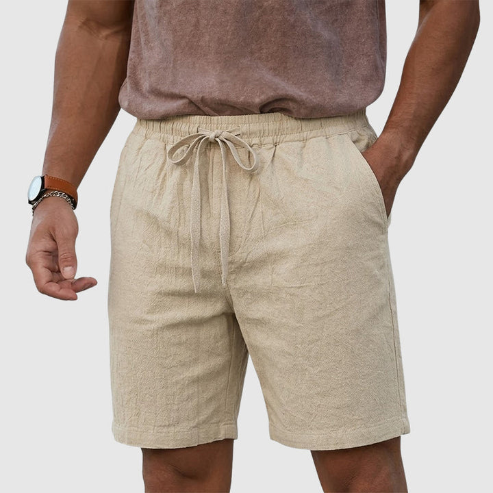  Model wearing easygoing men’s shorts with a clean everyday look on a plain background.