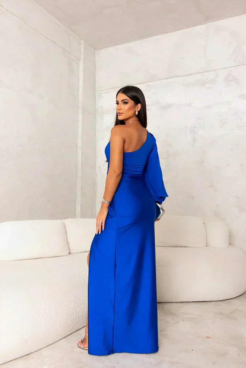  Woman showcasing a floor-length gown with elegant draping and modern styling on a plain background.