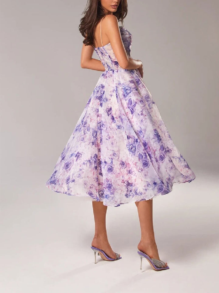  Female model wearing a midi dress with an all-over floral print on a plain background.