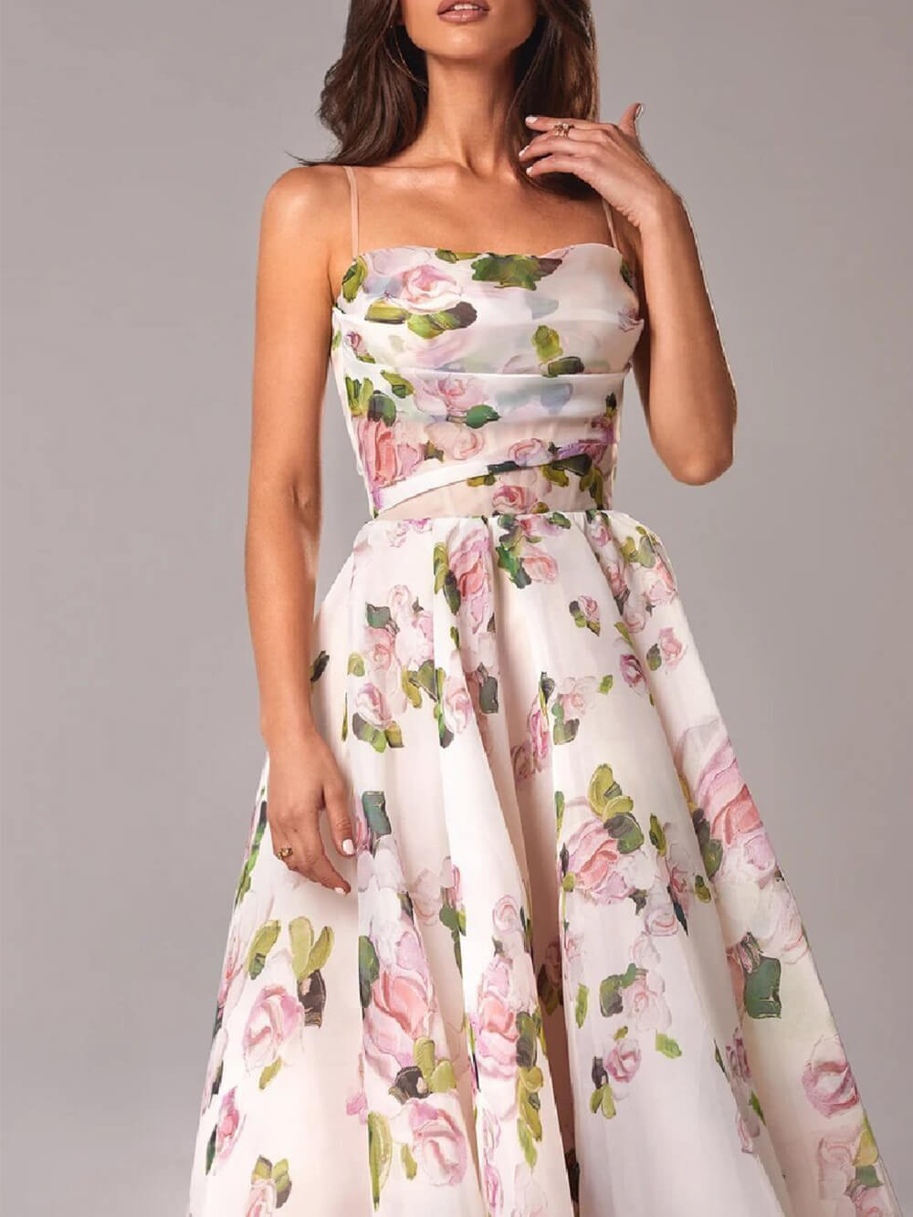  Woman displaying a lightweight floral dress with a feminine design on a plain background.