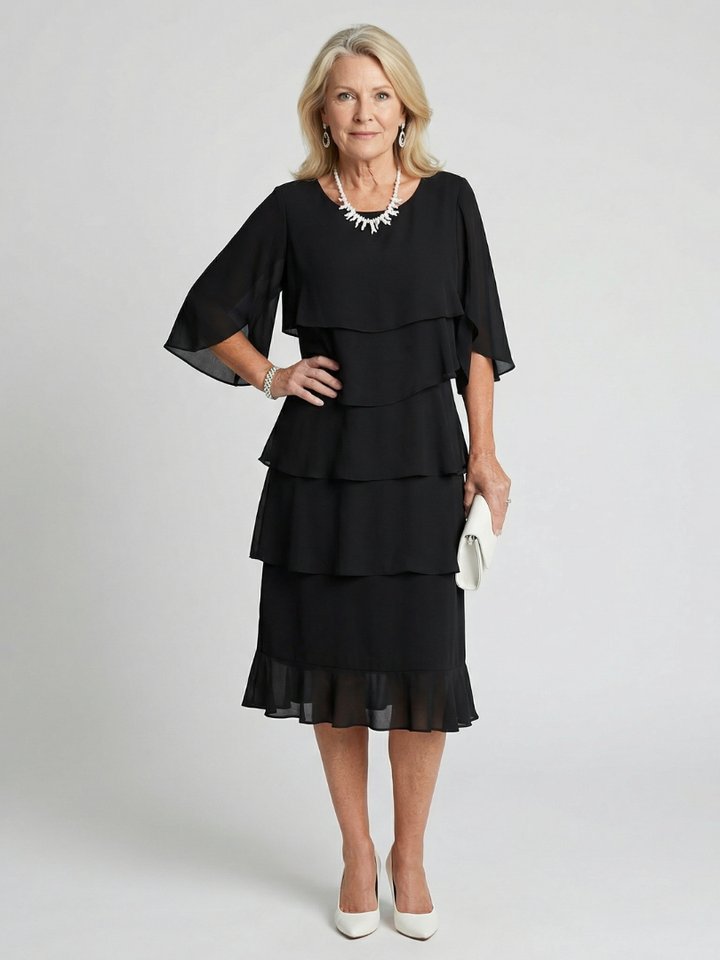 Female wearing a tiered flutter sleeve midi dress against a plain background.