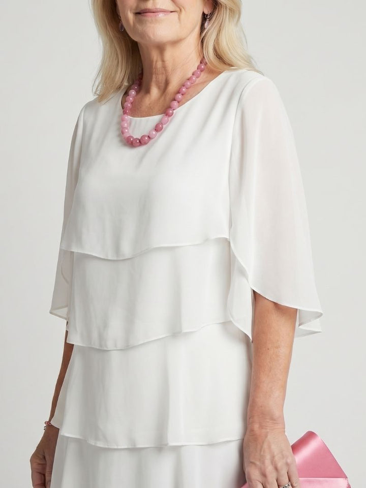 Woman in a midi dress featuring flowing layers and feminine sleeve details.
