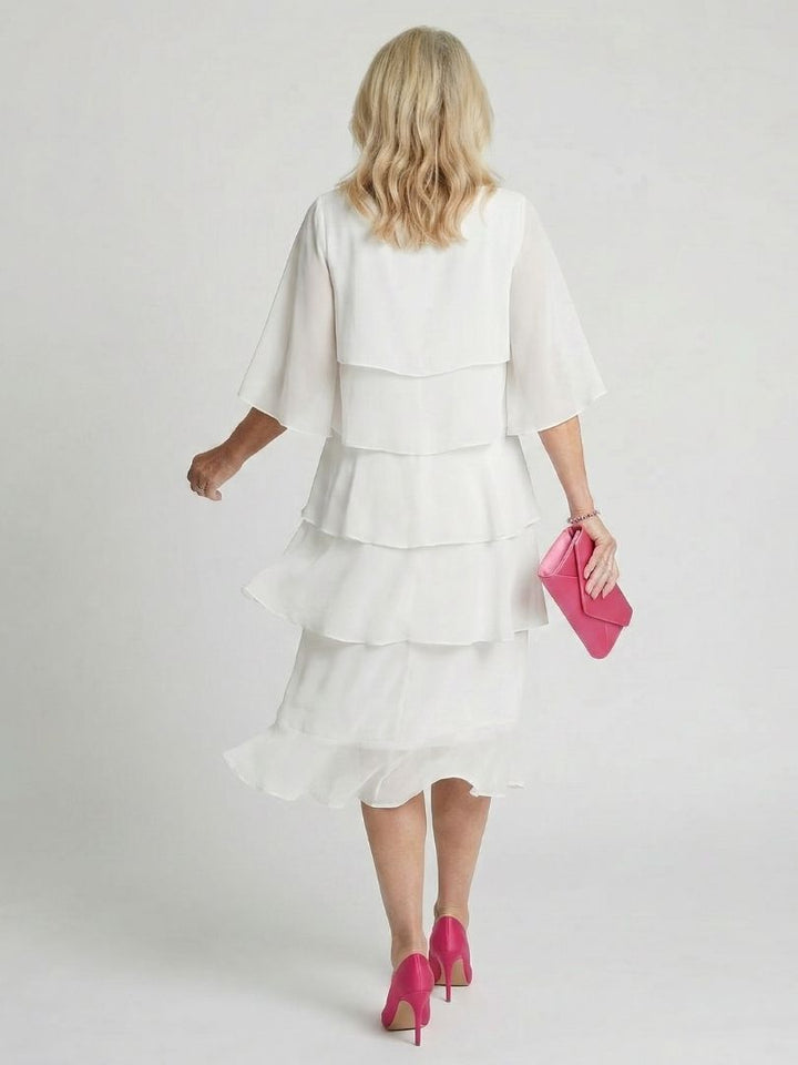 Female posing in a lightweight midi dress with flutter sleeves and layered texture.