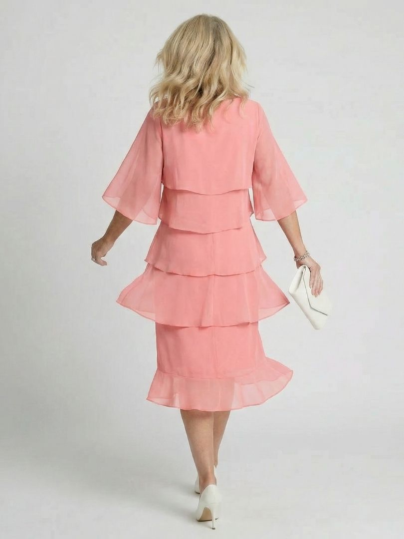 Woman in a flowing dress with layered tiers and classic round neckline.