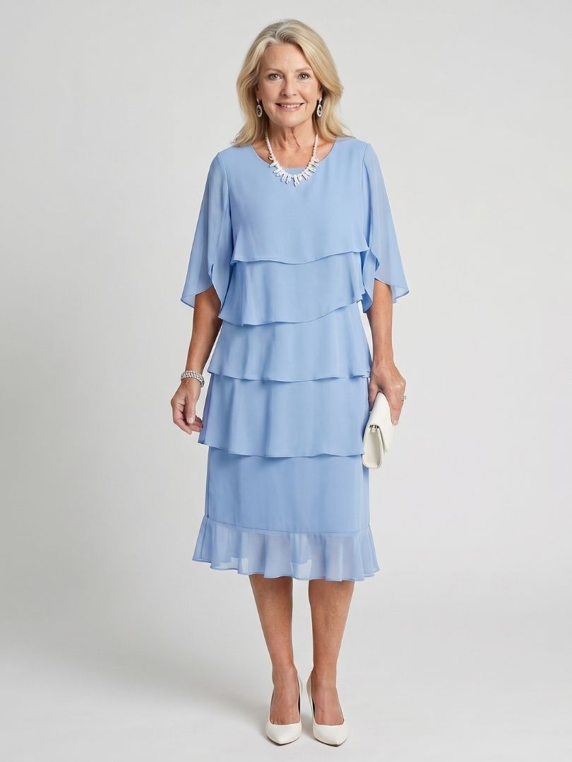 Woman showcasing a tiered midi dress with elegant movement on a plain backdrop.